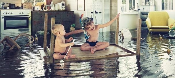 Kids floating on table in flooded living room - flood insurance