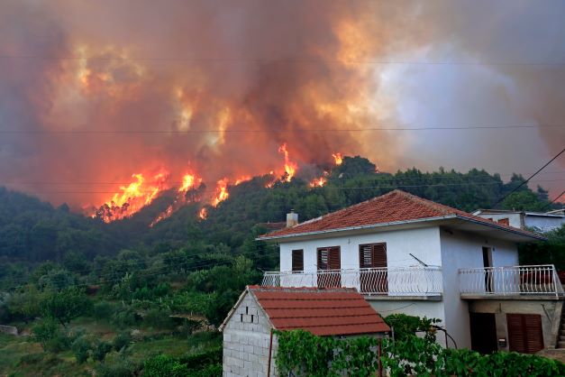 Wildfire on hillside in California with home in front - Brush Insurance